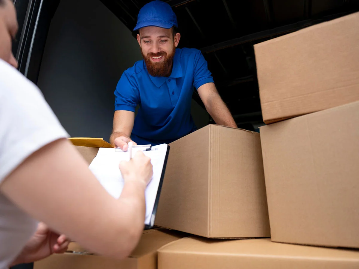 Repartidor entregando cajas desde un vehículo y solicitando confirmación en un documento.